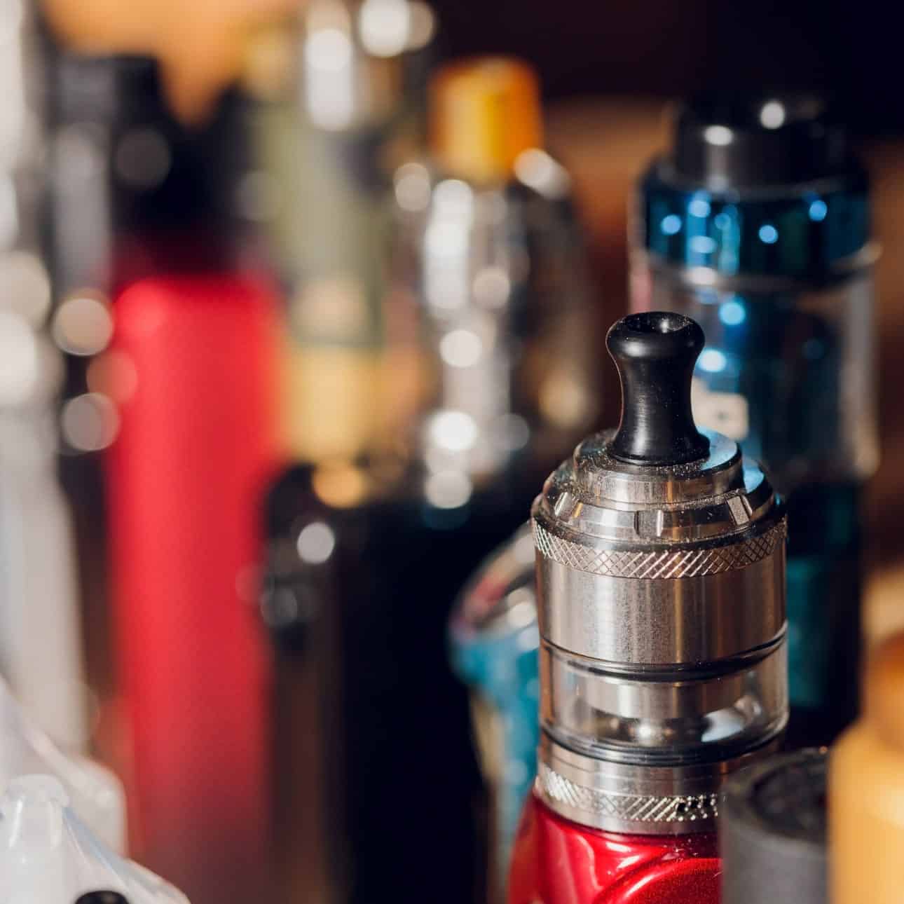 Vape device and e-liquid bottles on a bar counter, popular vaping accessories and supplies.