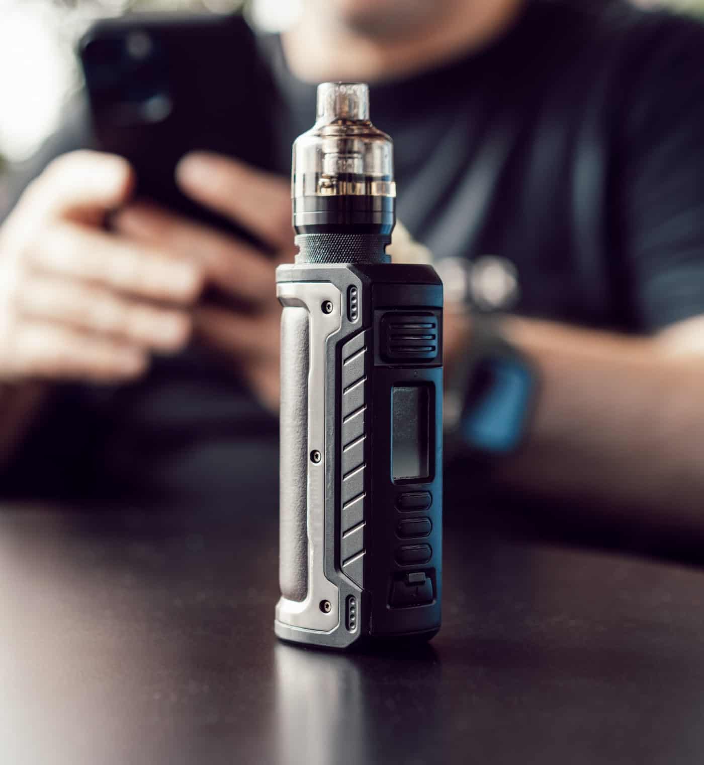 Modern vape mod with tank on black table for vaping enthusiasts and e-cigarette users.